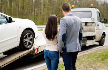 Couple near tow-truck picking up broken car